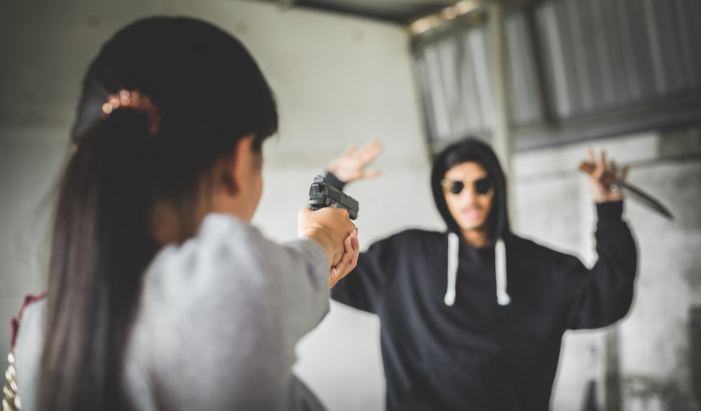 Woman pointing a shotgun at a thief, demonstrating defensive actions under Canadian law