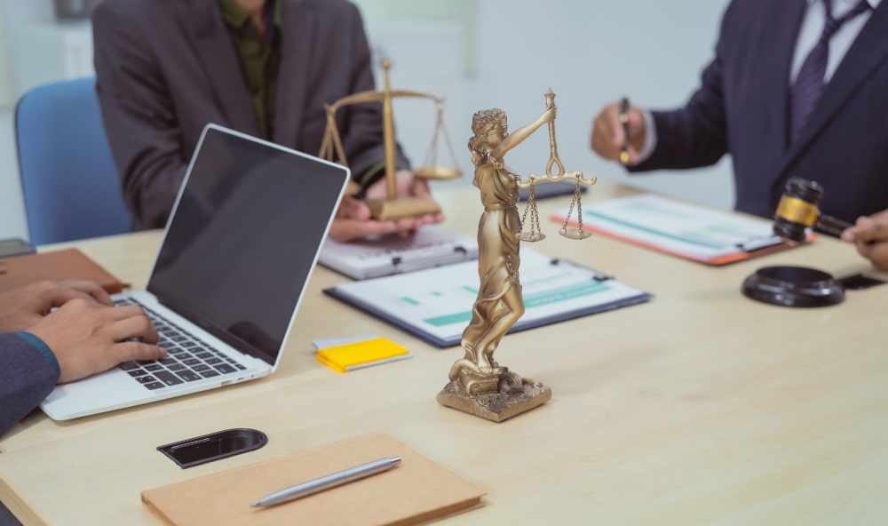 Three lawyers in a meeting at the table in an office, discussing defence strategies in assault with a weapon