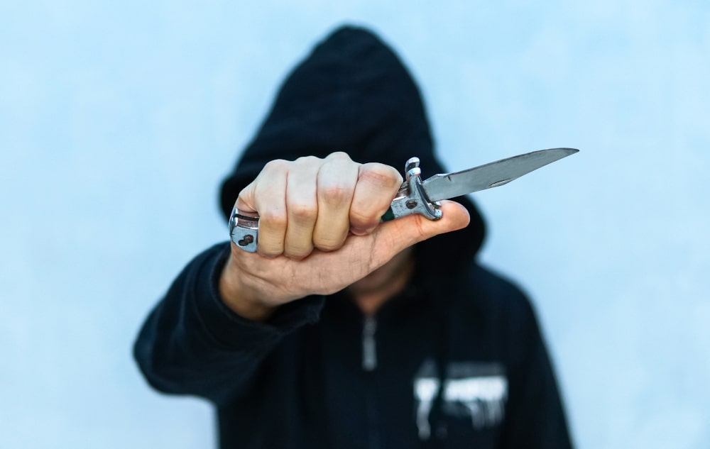 Youth Charges of Assault with a Weapon: A young man in a hoodie holding a knife symbolizing youth crime