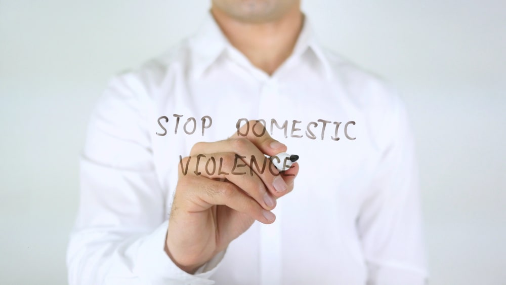 Help Stop Domestic Violence: Man Writing on Glass “Stop Domestic Violence”
