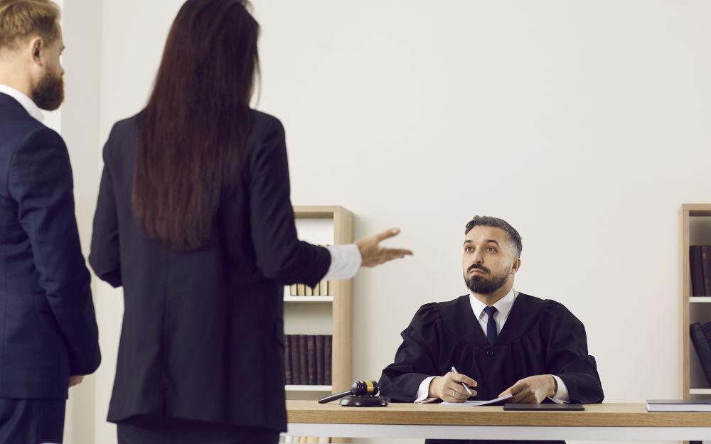 Judge listening to defence lawyer and accused in a Canadian courtroom, illustrating Crown discretion and early withdrawal of sexual assault charges before trial.
